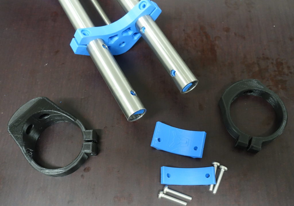 Benötigte Bauteile für das Anbringen der Spindelhalterung. Neben den beiden blau gedrukten Standardbauteilen muss je nach genutzter Werkzeugspindel noch eine spezielle Halterung (schwarze Teile) verwendet werden.